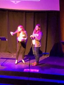 Business professional women presenting at conference, speaking on stage.